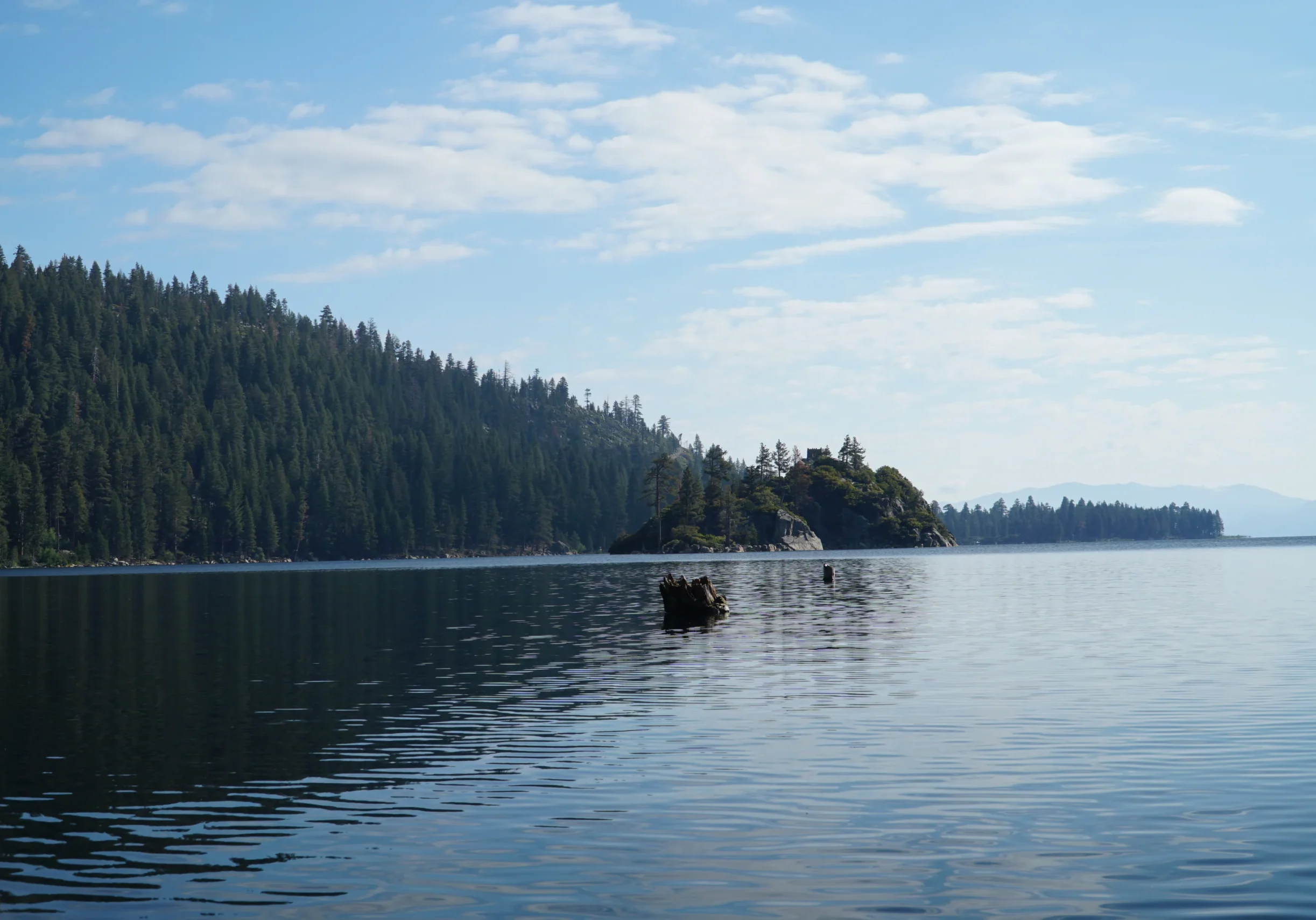 A calm deep blue lake with an evergreen forest in the background